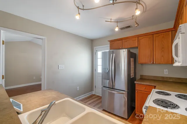a kitchen with stainless steel appliances granite countertop a refrigerator a stove and a sink with cabinets