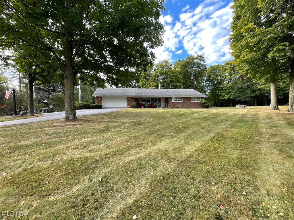 5990 Meese Road Northeast Louisville, OH 44641 - Photo 1 of 16 Ranch-style house featuring driveway, an attached garage, brick siding, a front lawn, and view of scattered trees