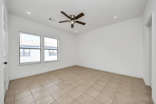 an empty room with windows and fan