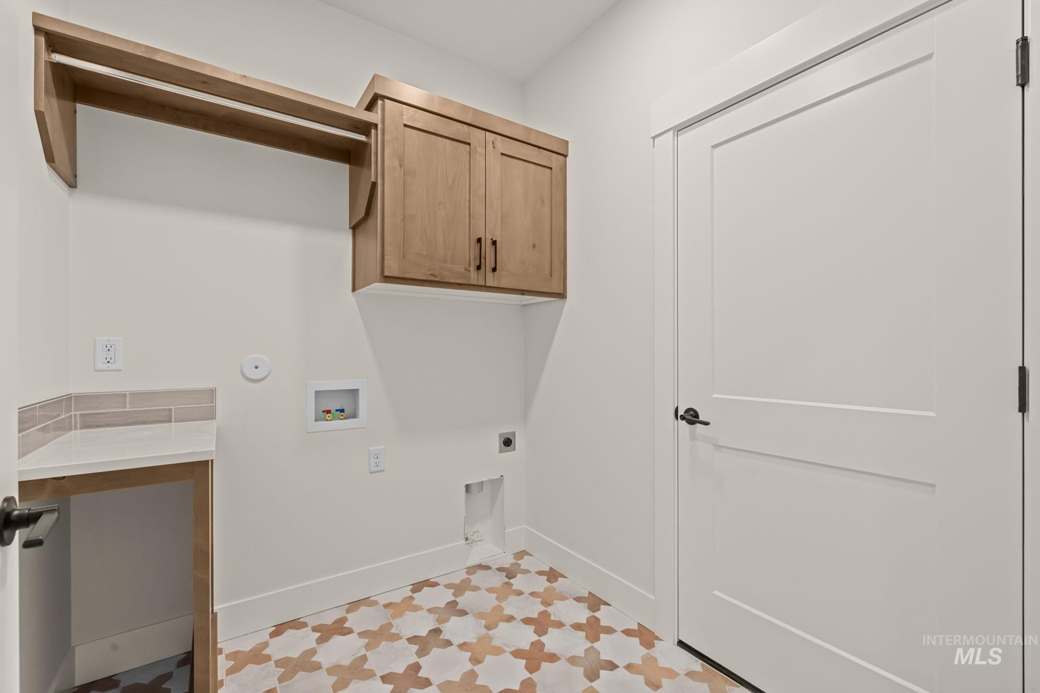 365 South Radiator Way Boise, ID 83716 - Photo 36 of 40 Built-in wood-finish cabinetry, countertop with tile backsplash, dedicated hanging rod, and patterned floor tiling