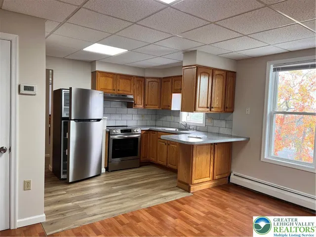 a kitchen with stainless steel appliances granite countertop a refrigerator a sink dishwasher a stove and a refrigerator with wooden floor