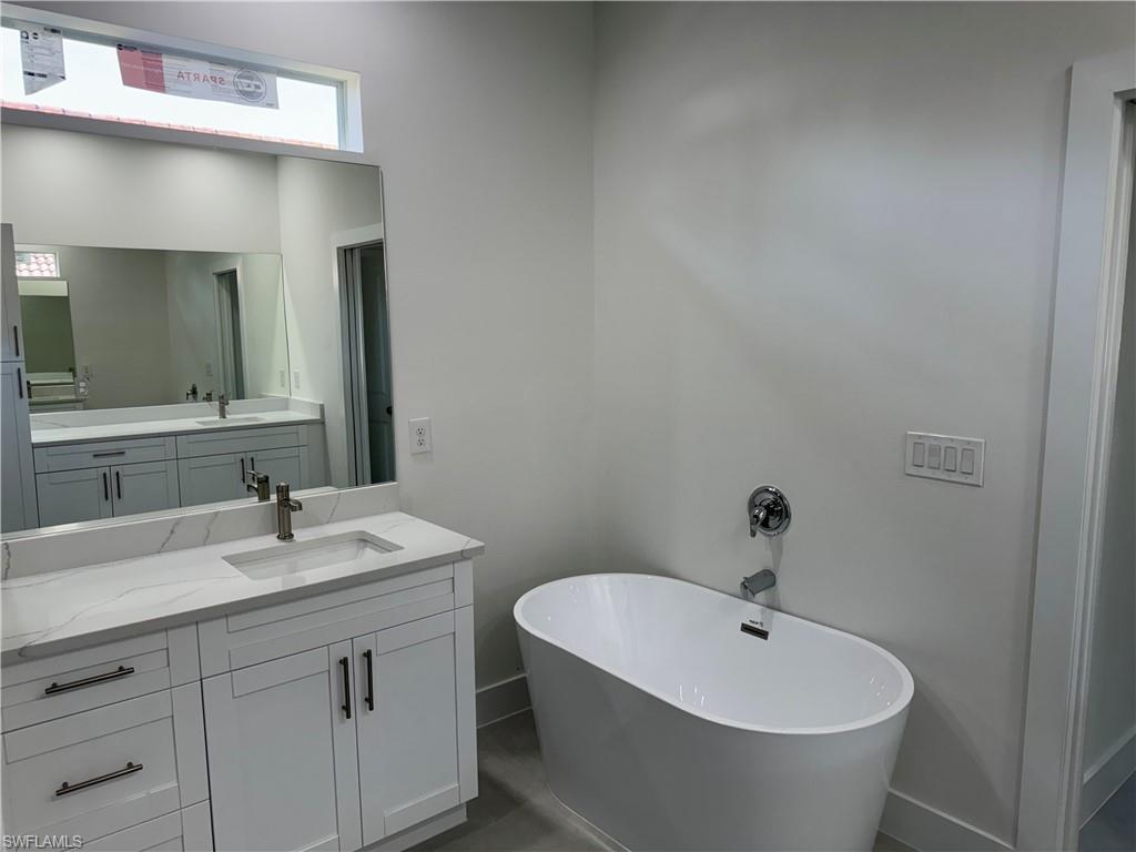 829 Albert Avenue Lehigh Acres, FL 33971 - Photo 17 of 27 a bathroom with a white tub a sink and mirror