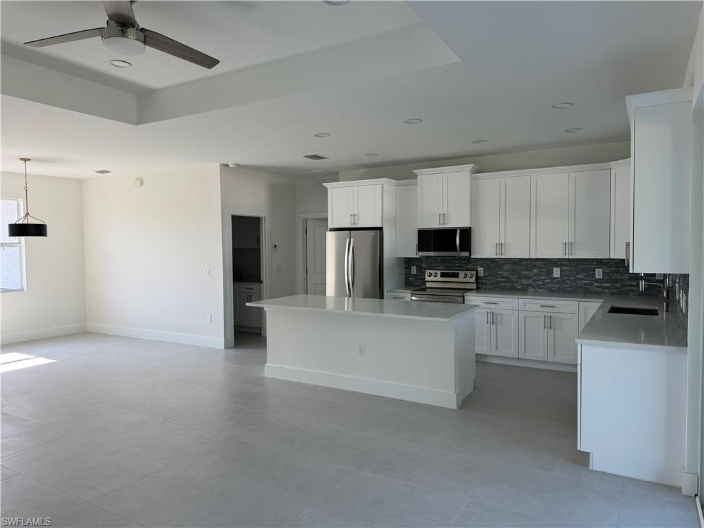 829 Albert Avenue Lehigh Acres, FL 33971 - Photo 9 of 27 a kitchen with stainless steel appliances granite countertop a refrigerator a stove top oven a sink and dishwasher with white cabinets