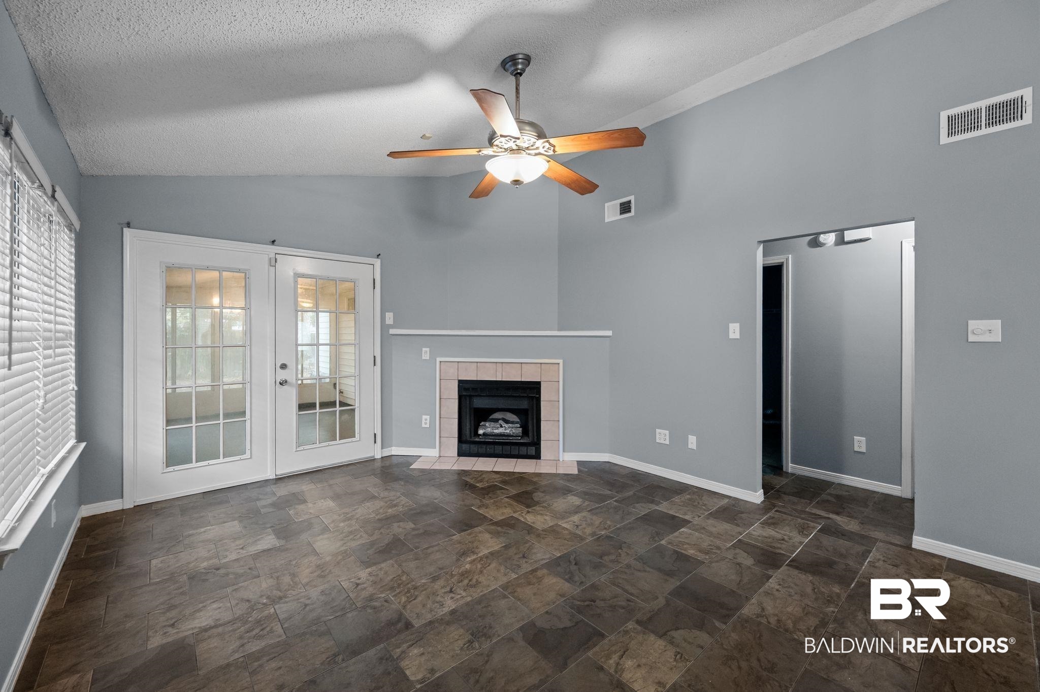 3744 Pepper Ridge Drive Mobile, AL 36693 - Photo 8 of 29 Unfurnished living room with vaulted ceiling, a fireplace, ceiling fan, a textured ceiling, and stone finish flooring