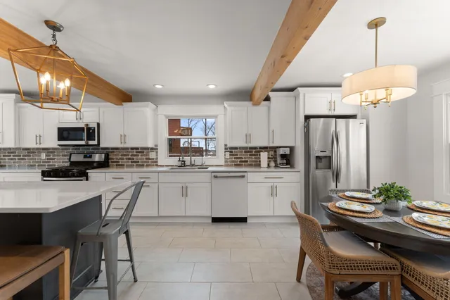 a kitchen with stainless steel appliances a table chairs and a refrigerator