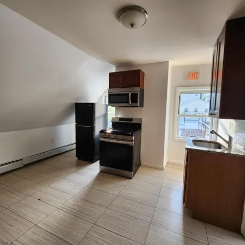 a kitchen with granite countertop a refrigerator and a stove top oven