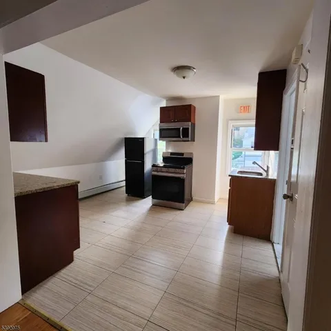 a kitchen with granite countertop a refrigerator and a stove top oven