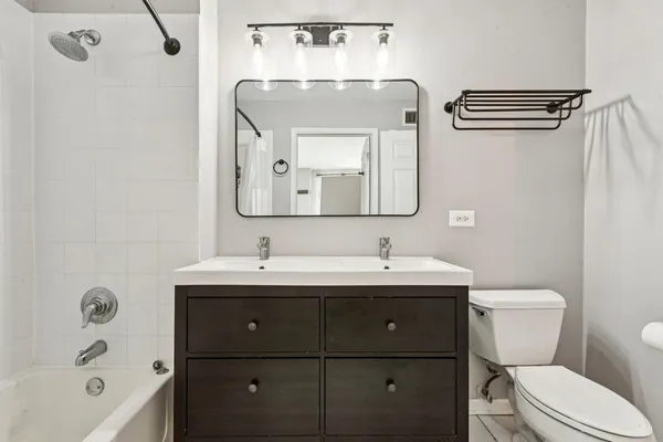 a bathroom with a toilet sink double vanity and mirror