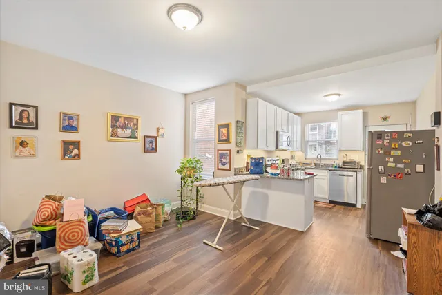 a living room with stainless steel appliances furniture and a wooden floor
