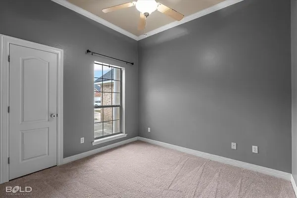 an empty room with chandelier fan and windows