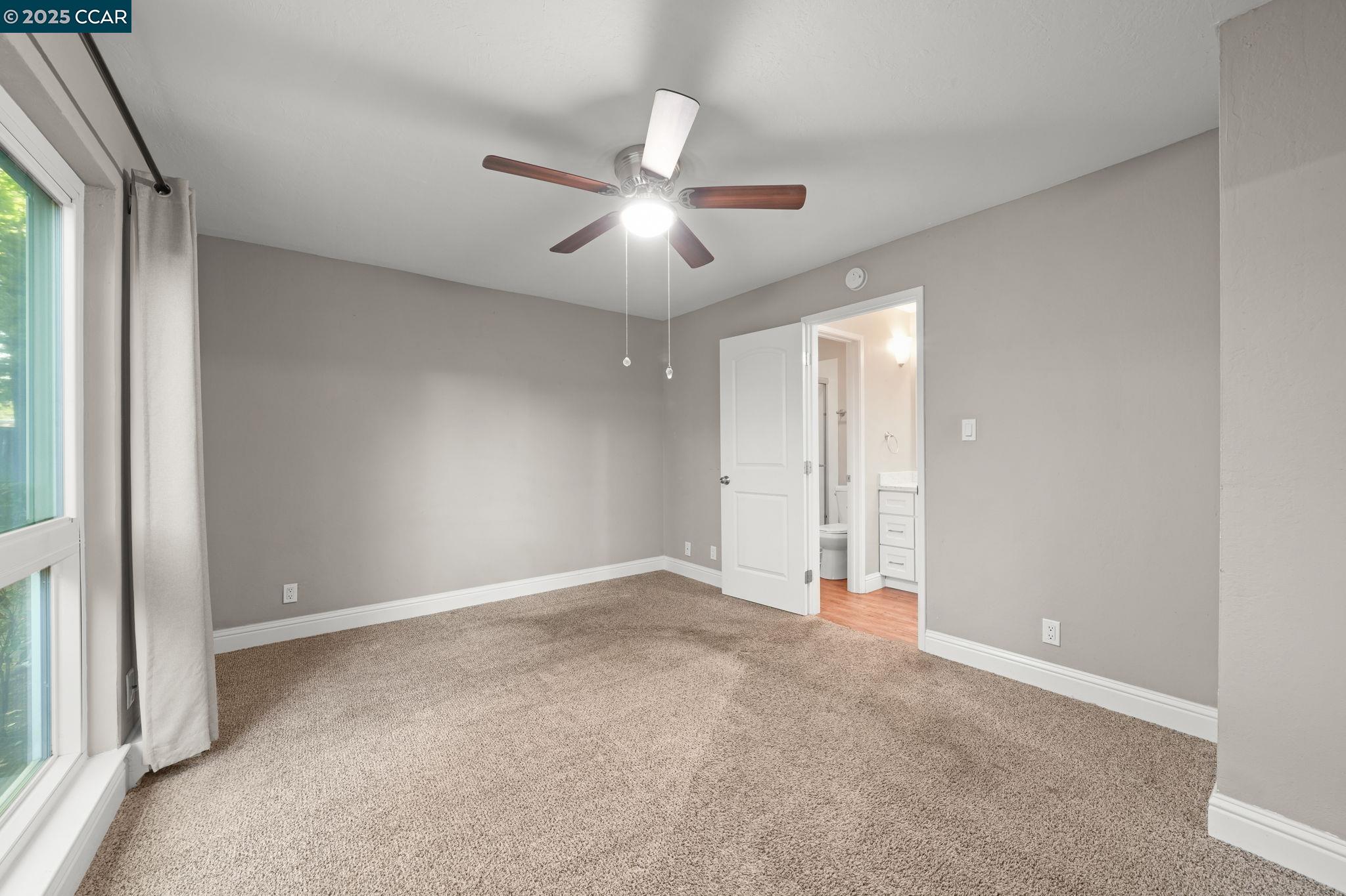 1036 Oak Grove Road, Unit 21 Concord, CA 94518 - Photo 14 of 23 an empty room with chandelier fan and windows