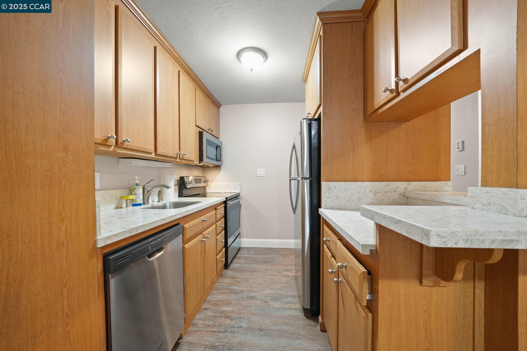 1036 Oak Grove Road, Unit 21 Concord, CA 94518 - Photo 3 of 23 a kitchen with stainless steel appliances granite countertop a sink and dishwasher a refrigerator with wooden floor