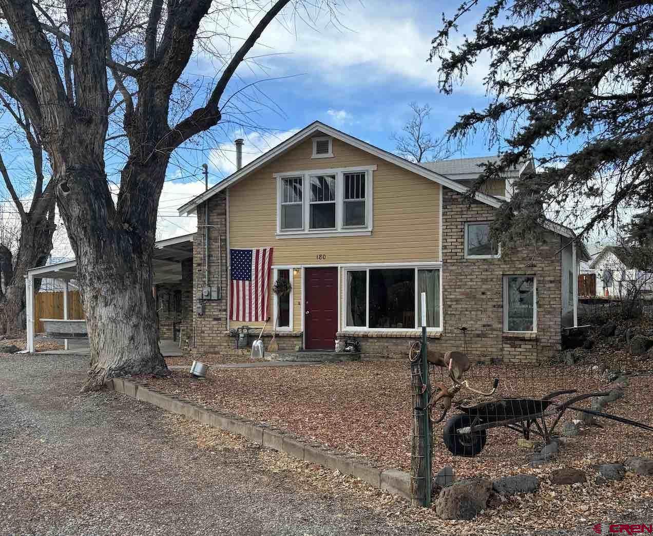 a front view of a house with yard tree and wooden fence