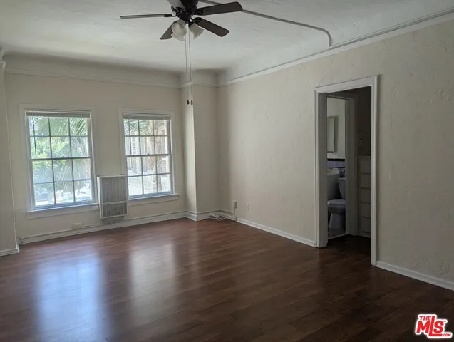 an empty room with wooden floor chandelier fan and windows
