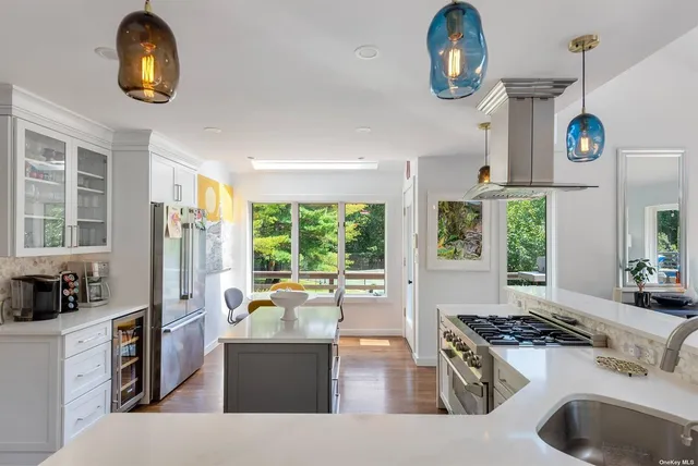a kitchen with a stove a refrigerator a sink and a dining table with garden view