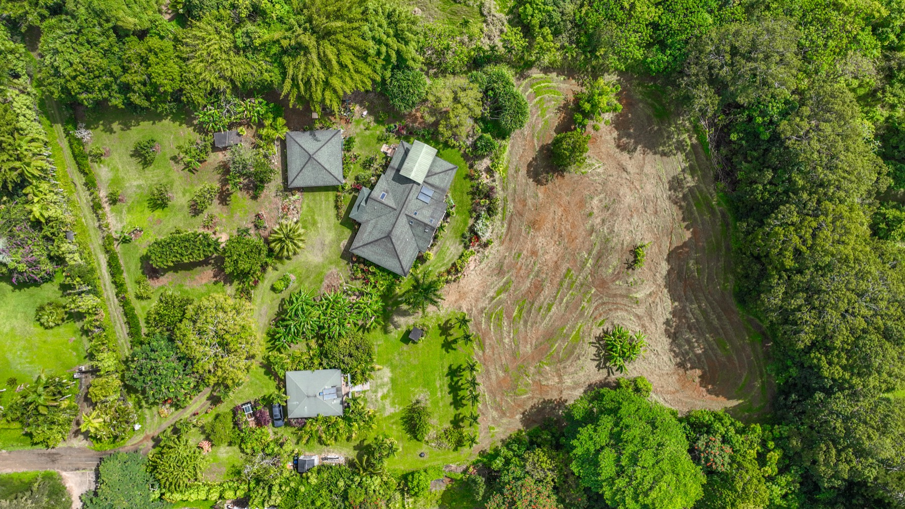an aerial view of residential house with outdoor space and trees all around
