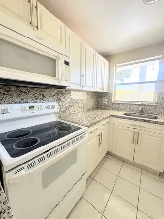 a kitchen with granite countertop white cabinets and white appliances