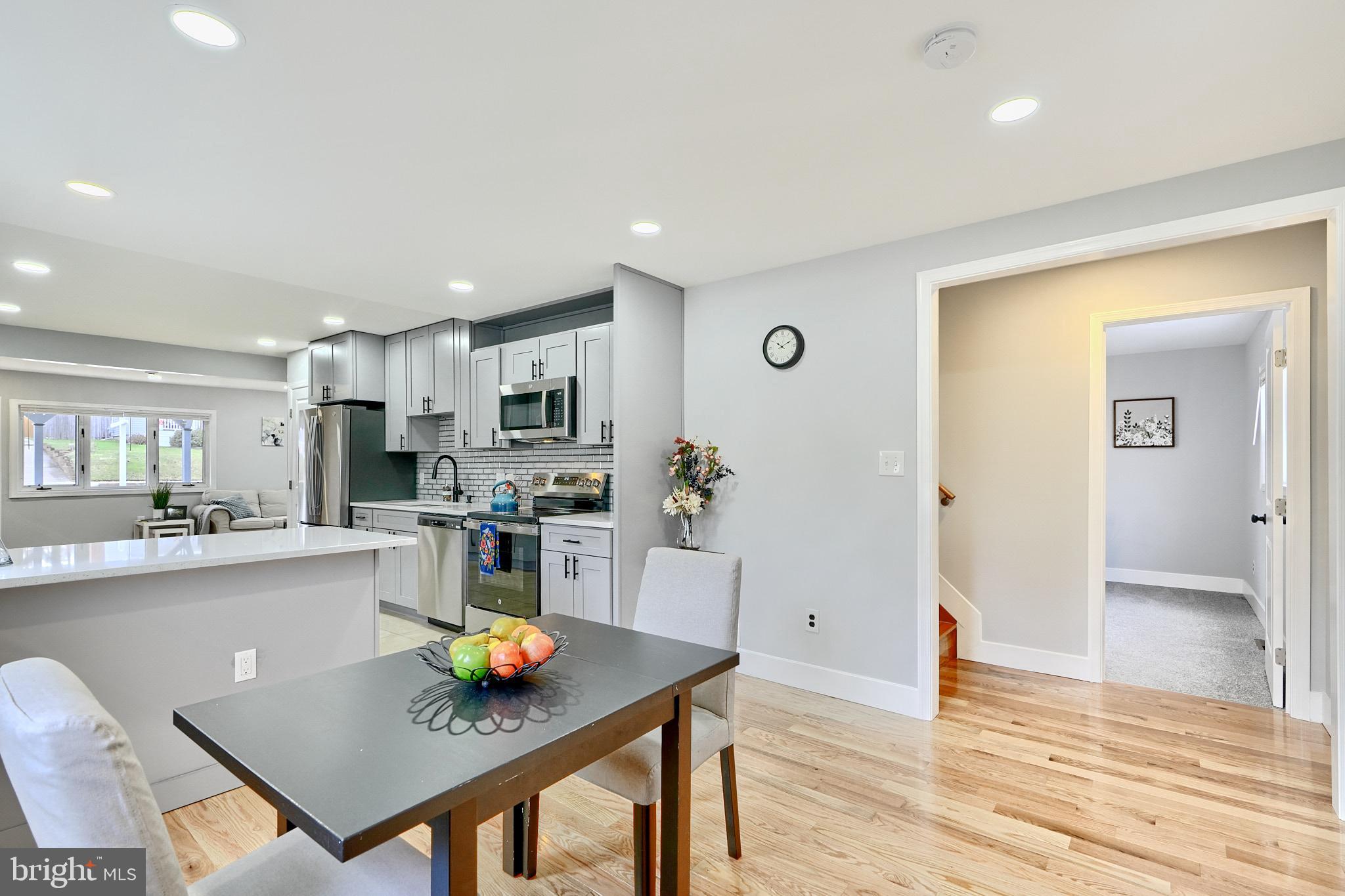 709 Fuselage Avenue Baltimore, MD 21221 - Photo 16 of 36 a kitchen with stainless steel appliances granite countertop a stove a refrigerator a sink a dining table and chairs with wooden floor