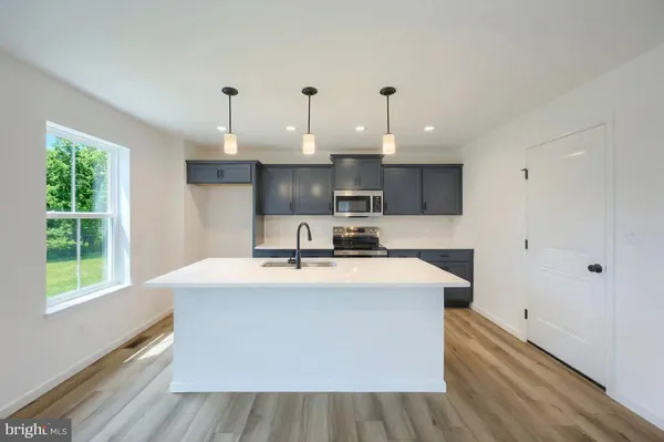 a kitchen with kitchen island a stove a sink dishwasher and white cabinets with wooden floor