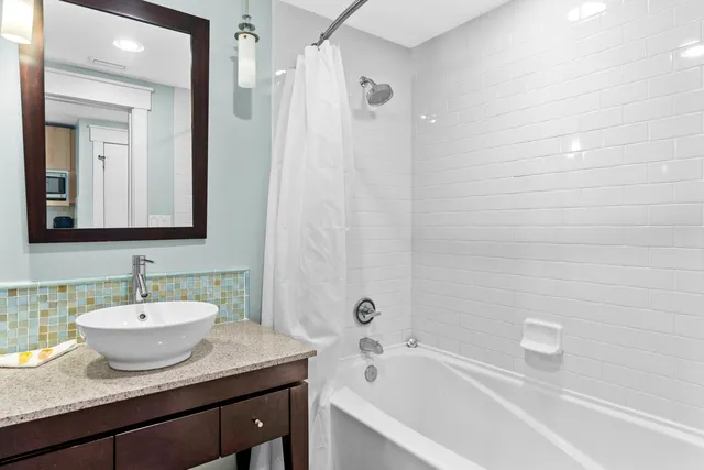 a bathroom with a granite countertop sink mirror and bathtub