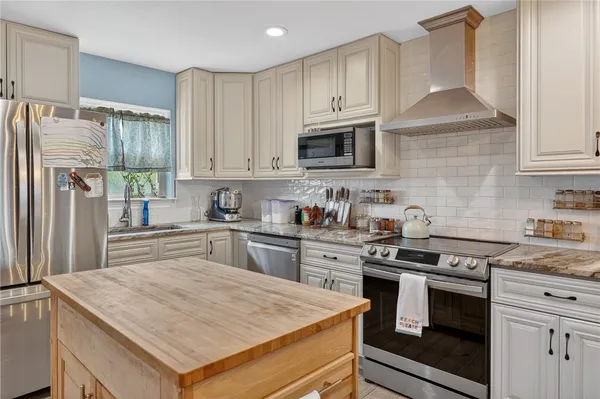 a kitchen with granite countertop a stove sink and refrigerator