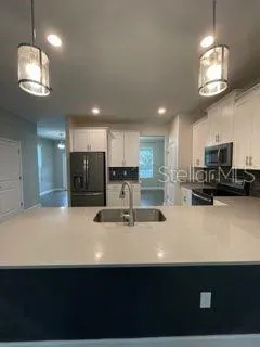 a kitchen with stainless steel appliances a sink dishwasher a refrigerator a microwave oven and a sink with cabinets