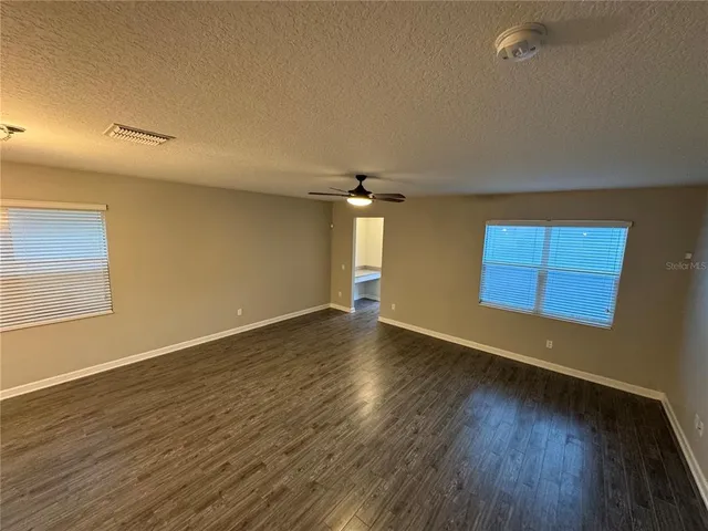 an empty room with wooden floor and windows