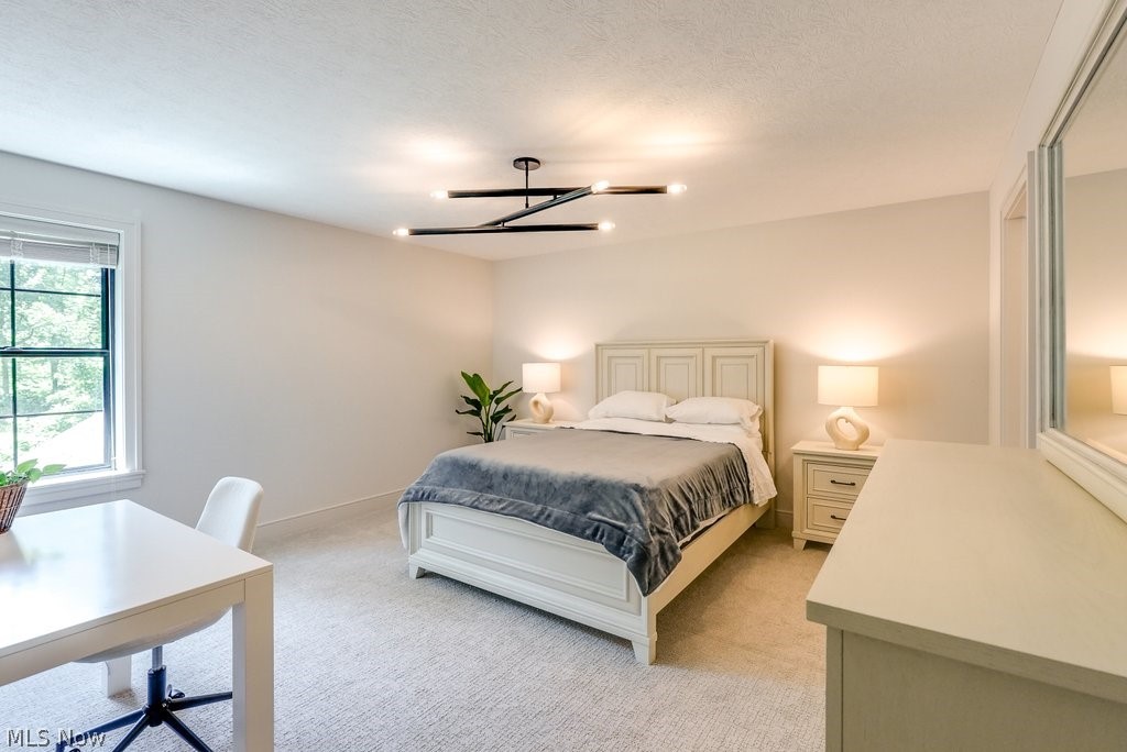 3040 Lander Road Pepper Pike, OH 44124 - Photo 25 of 38 Bedroom featuring light colored carpet, a chandelier, and a textured ceiling