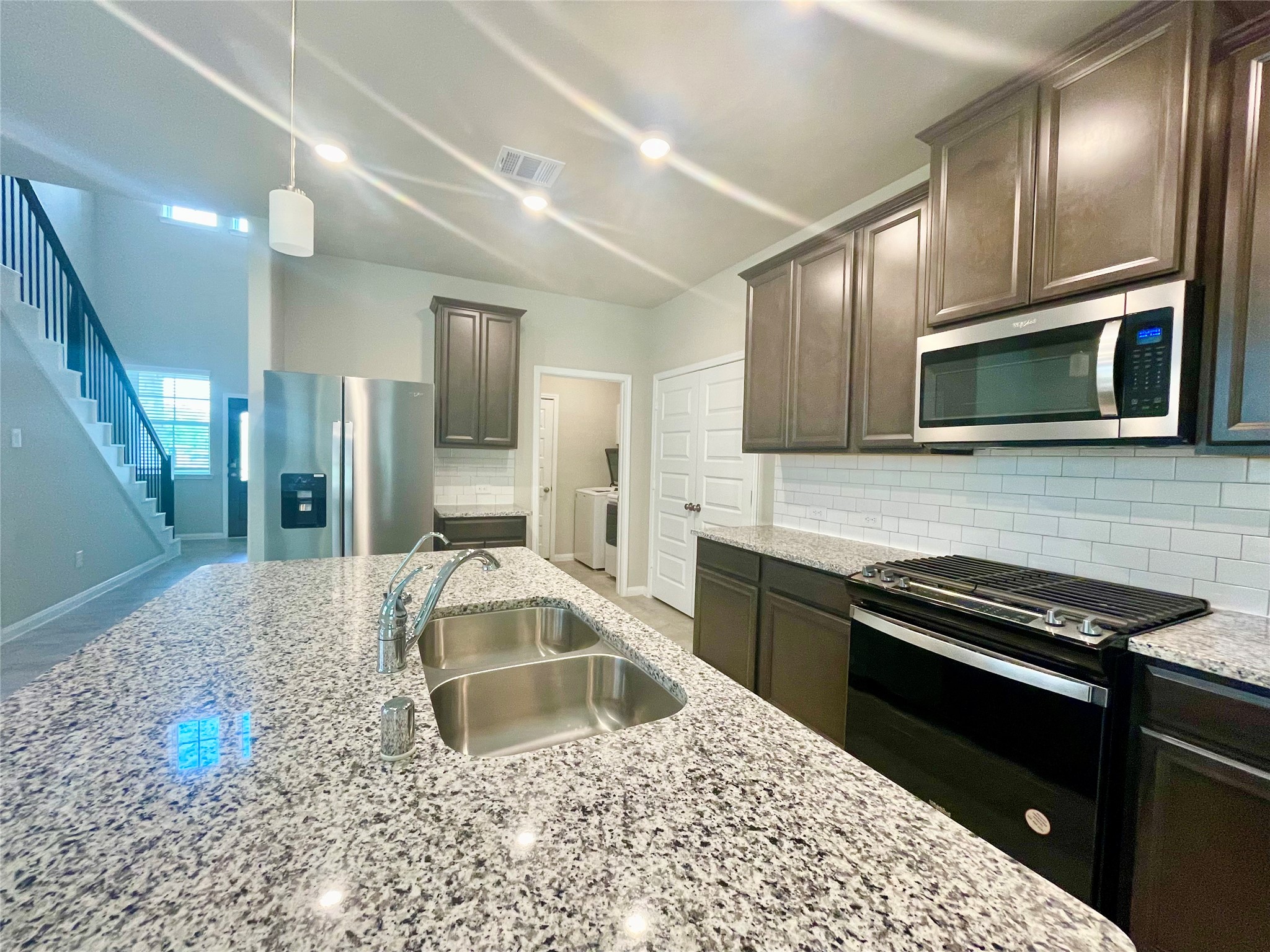 17526 Rosette Grass Conroe, TX 77385 - Photo 10 of 49 a kitchen with stainless steel appliances kitchen island granite countertop a stove a sink and a microwave