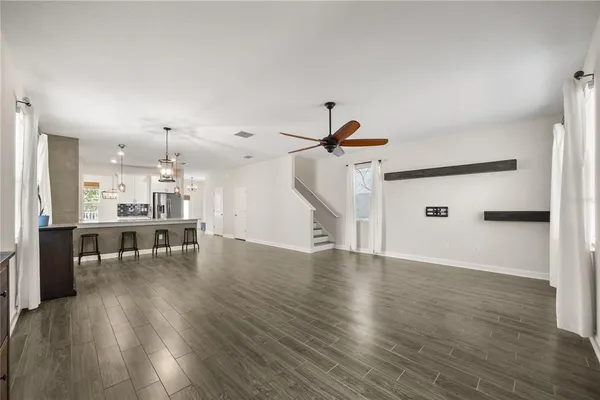 an empty room with wooden floor a ceiling fan and windows