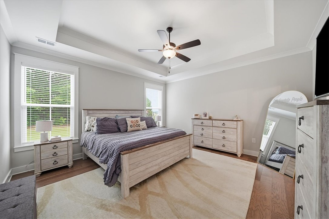 214 Timothy Court Anderson, SC 29621 - Photo 25 of 43 Recessed lighting and tray ceiling enhance this serene bedroom, featuring warm hardwood floors.