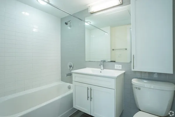 a bathroom with a toilet a sink a mirror a bathtub and vanity