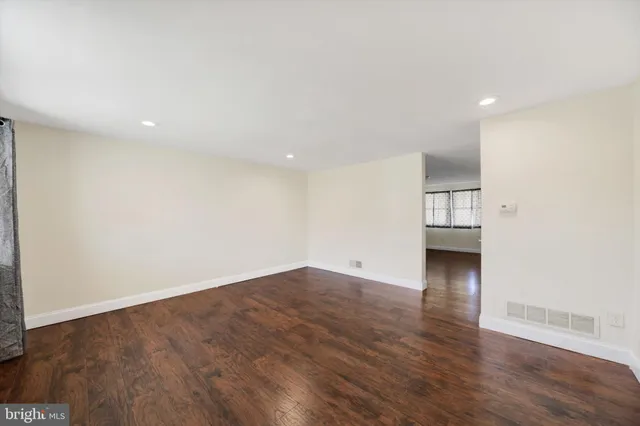 a view of empty room with wooden floor and window