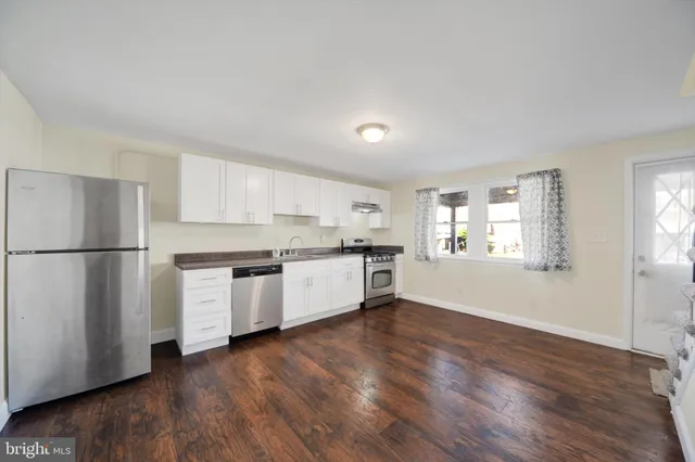 a kitchen with granite countertop white cabinets and wooden floor