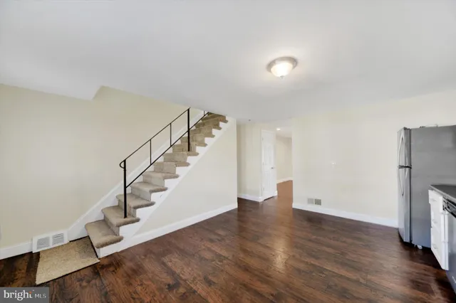 a view of an empty room with wooden floor and stairs