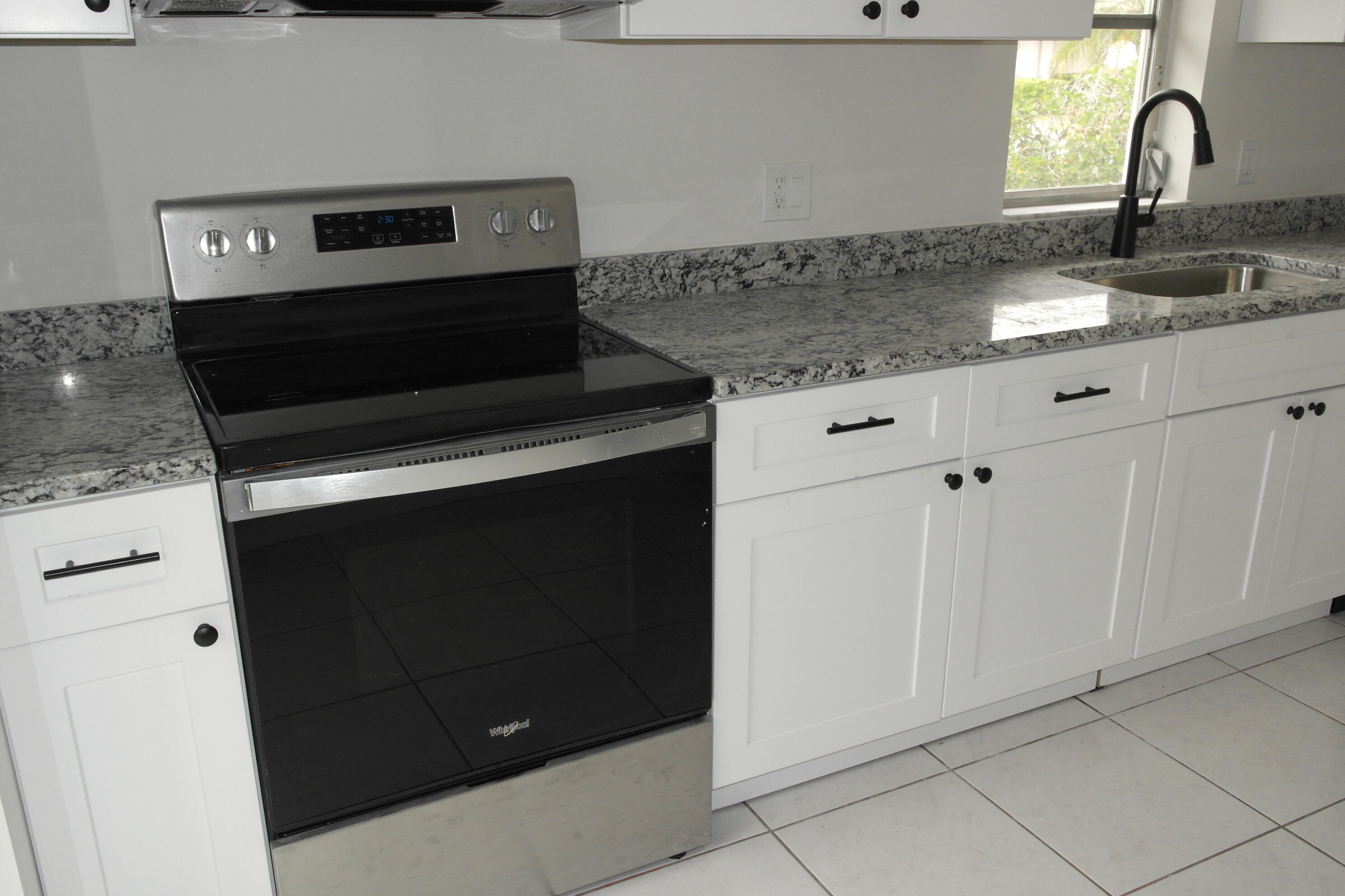 18890 Candlewick Drive, Unit B Boca Raton, FL 33496 - Photo 3 of 16 a kitchen with granite countertop white cabinets and black appliances