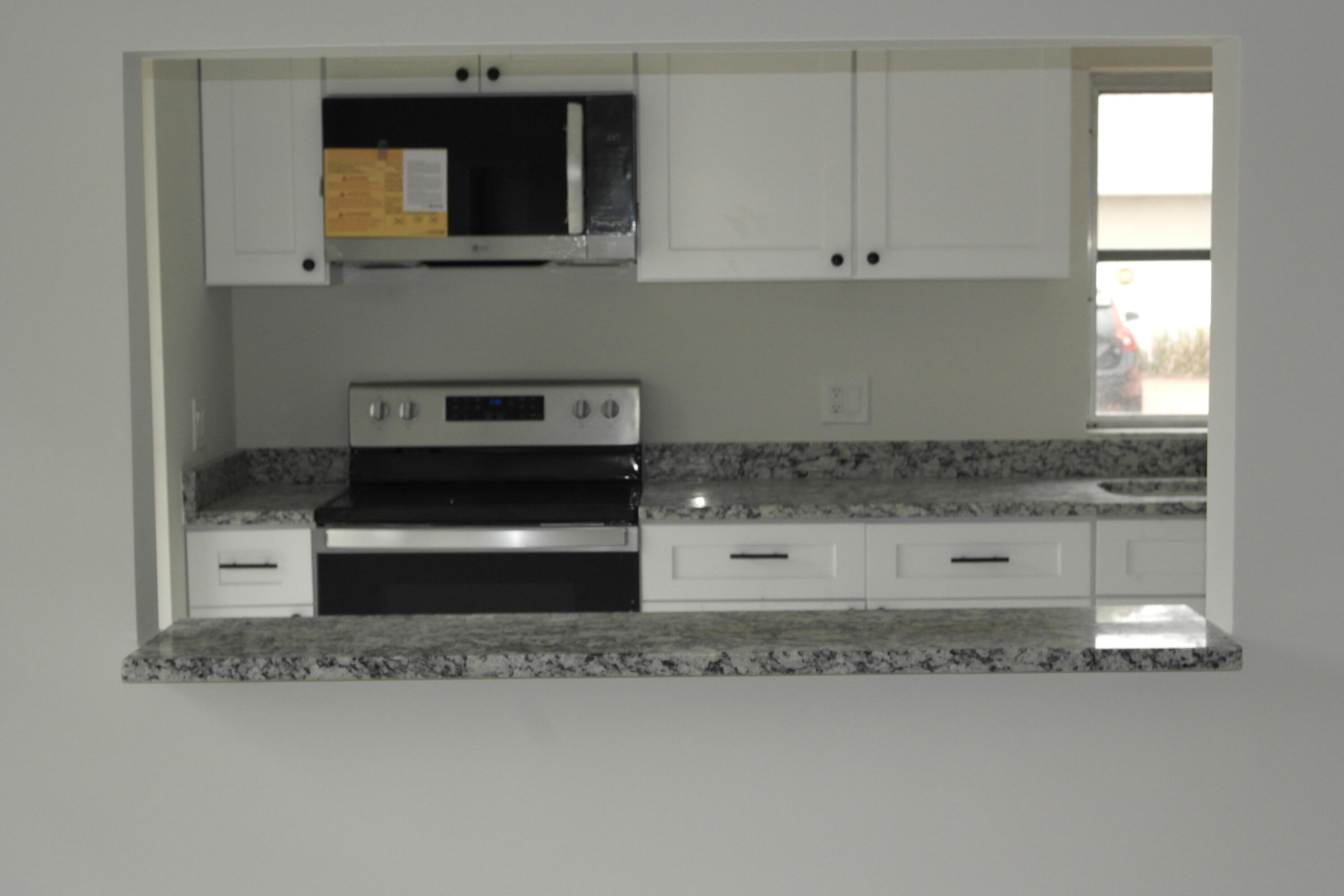 18890 Candlewick Drive, Unit B Boca Raton, FL 33496 - Photo 5 of 16 a kitchen with granite countertop a stove and a microwave