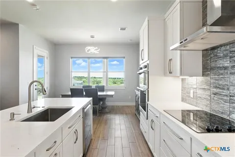 a kitchen with granite countertop a sink a counter space appliances and cabinets