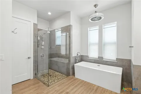 a bathroom with a tub a sink and a large mirror