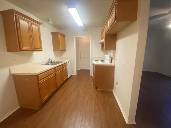 a kitchen with sink a refrigerator and wooden floor