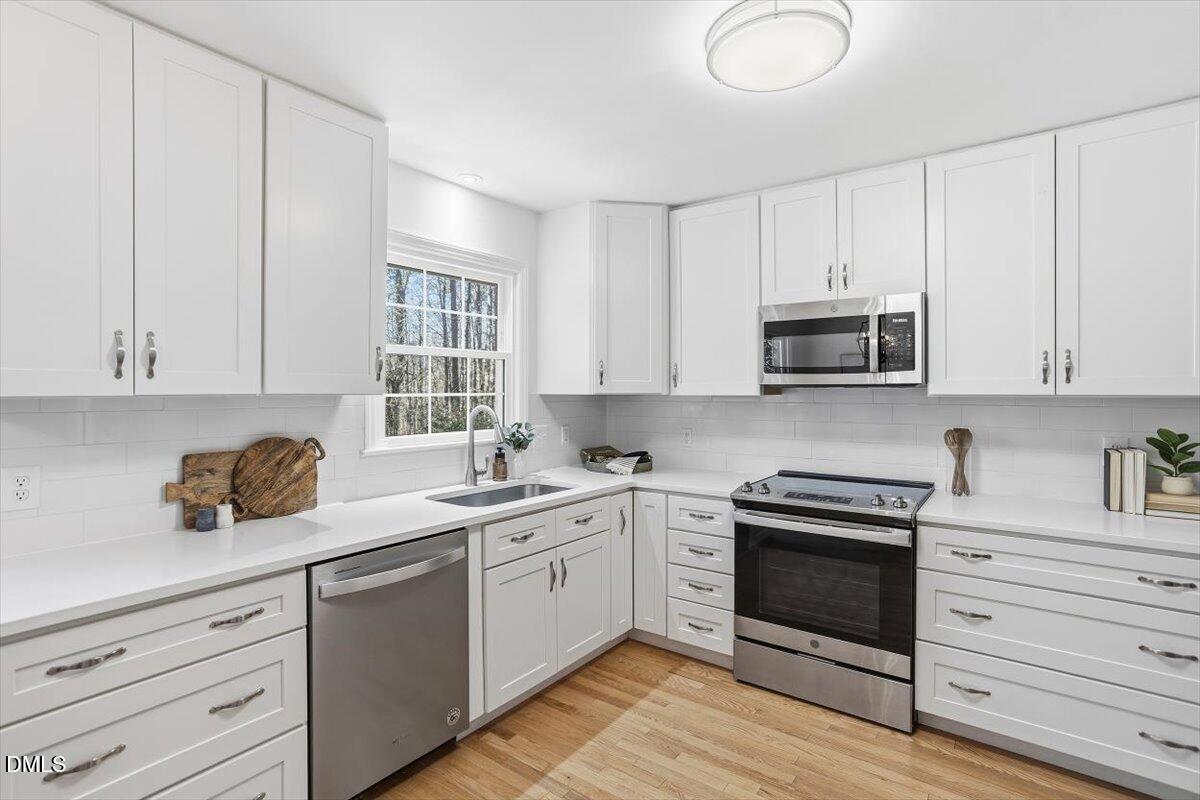 2828 McDowell Road Durham, NC 27705 - Photo 9 of 45 a kitchen with white cabinets stainless steel appliances and sink