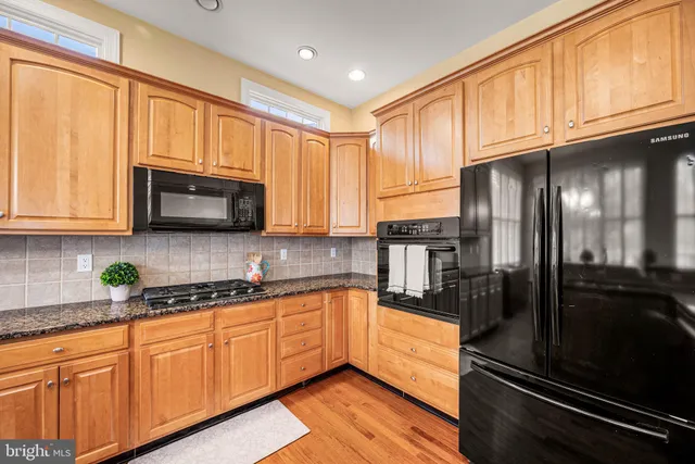 a kitchen with stainless steel appliances granite countertop a refrigerator a oven a sink dishwasher and white cabinets with wooden floor