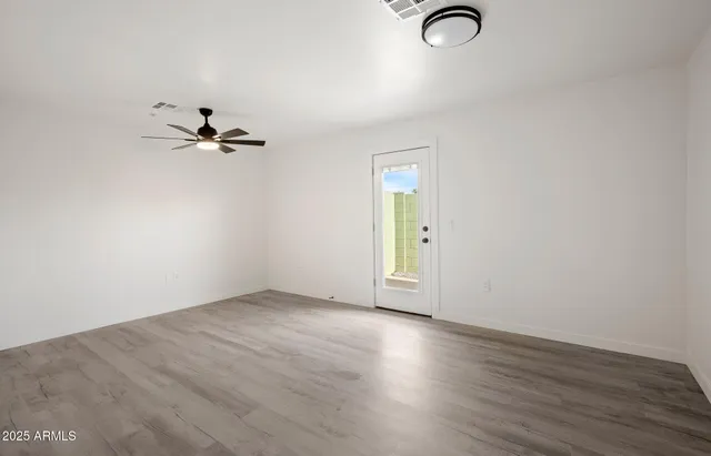 an empty room with wooden floor closet and windows