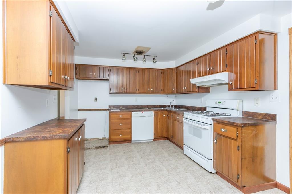 419 Manor Road Delmont, PA 15626 - Photo 16 of 30 a kitchen with granite countertop wooden cabinets a sink a stove and a window