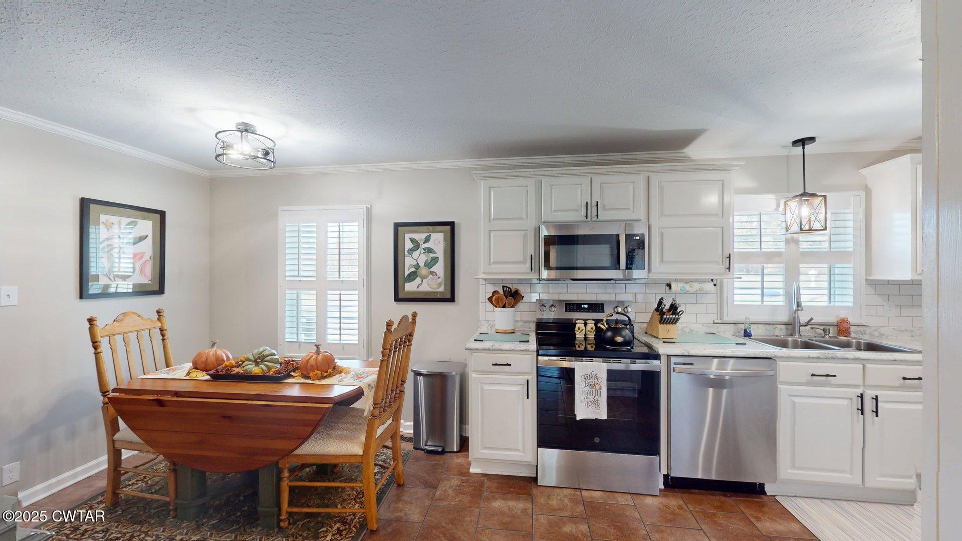 302 Flora Circle Newbern, TN 38059 - Photo 8 of 26 a kitchen with stainless steel appliances kitchen island granite countertop a sink dishwasher a stove a refrigerator with a dining table and chairs