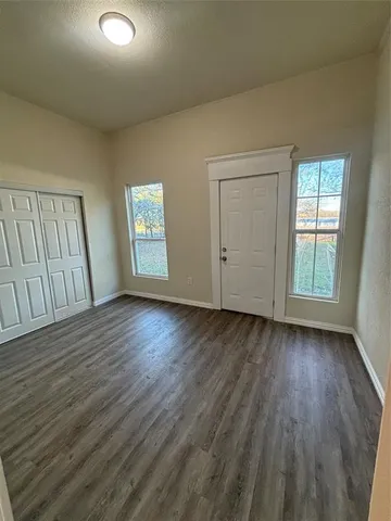 an empty room with wooden floor and window