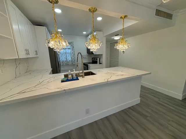 a room with kitchen island a chandelier and wooden floor