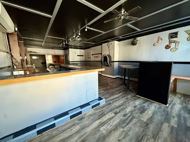 a view of an empty room with wooden floor and window