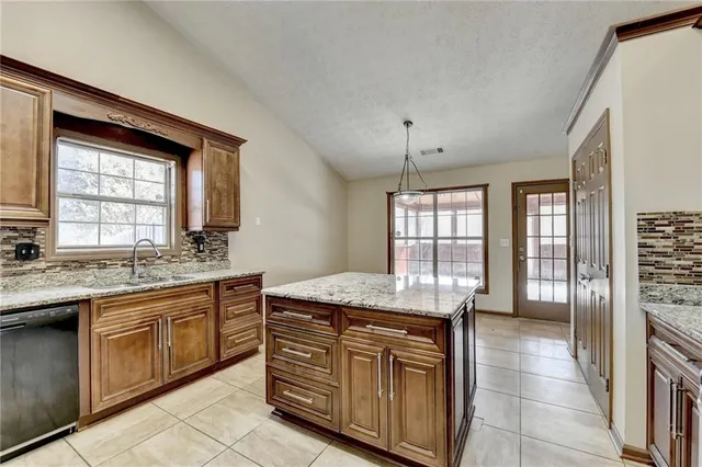 a kitchen with granite countertop a sink stove and refrigerator