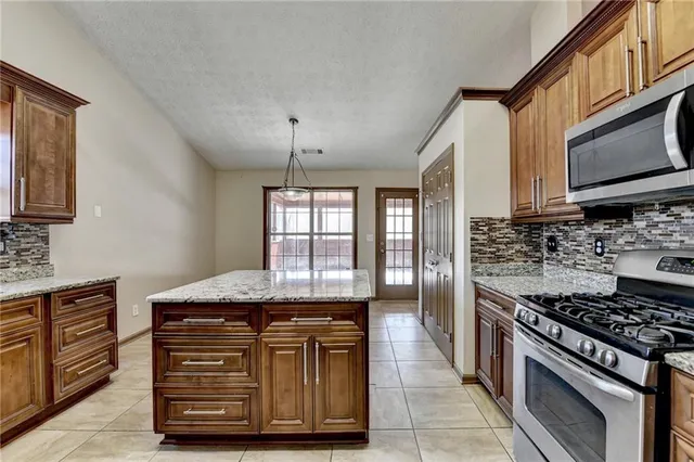 a kitchen with stainless steel appliances granite countertop a refrigerator a sink a stove and washer